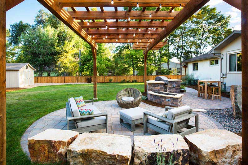 A stone patio with a wooden pergola overhead.